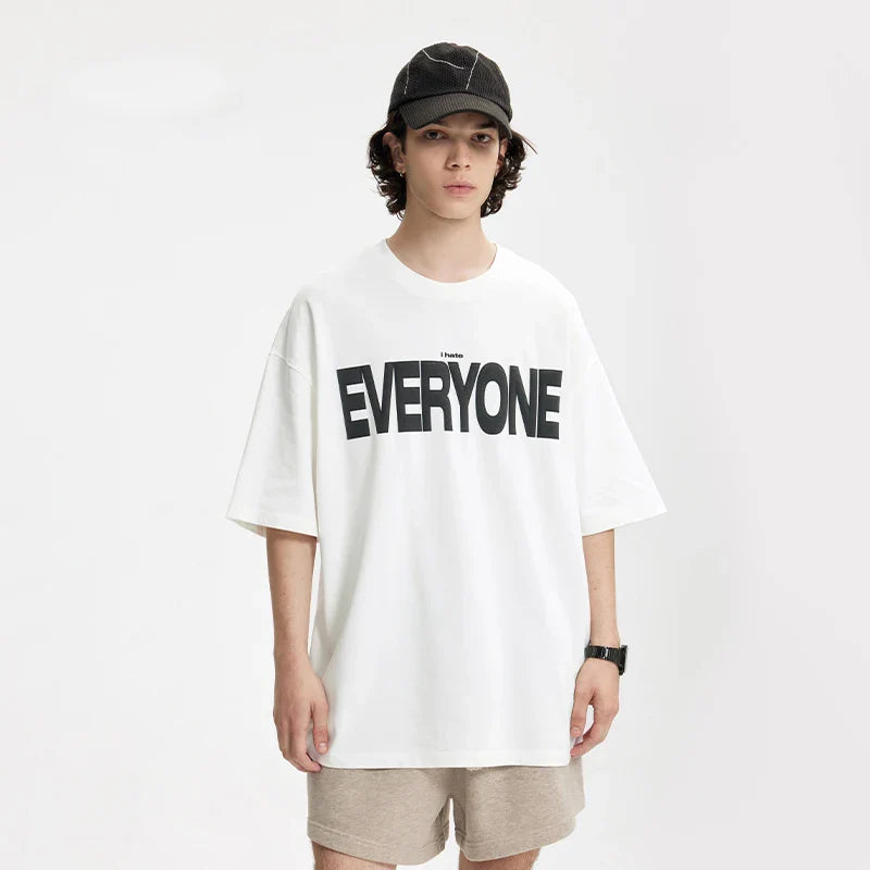 Model wearing the white EVERYONE Oversized T-Shirt in a gray background