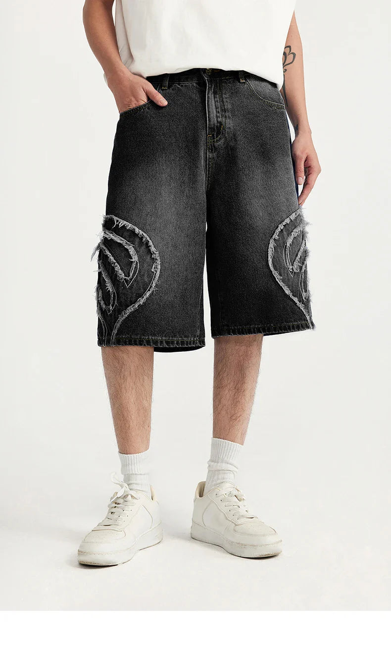 Model wearing the black Denim Patchwork Shorts in a gray background