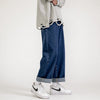 Grey torn shirt, wide blue jeans, white Nike shoes, minimalist white background.