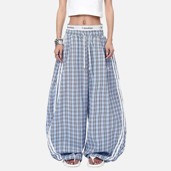 Person wearing blue plaid pants with white stripes on a white background