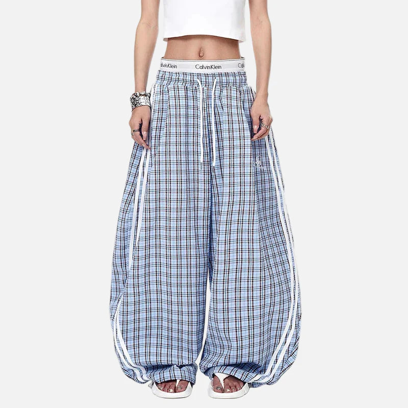 Person wearing blue plaid pants with white stripes on a white background