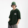 Moel wearing the green The Unity T-Shirt in a gray background