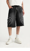 Model wearing the black Denim Patchwork Shorts in a gray background 